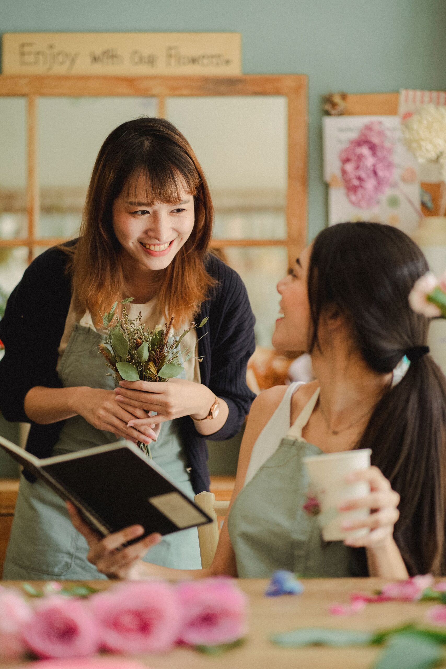 Cheerful multiethnic female florists smiling and talking during work day in floral shop